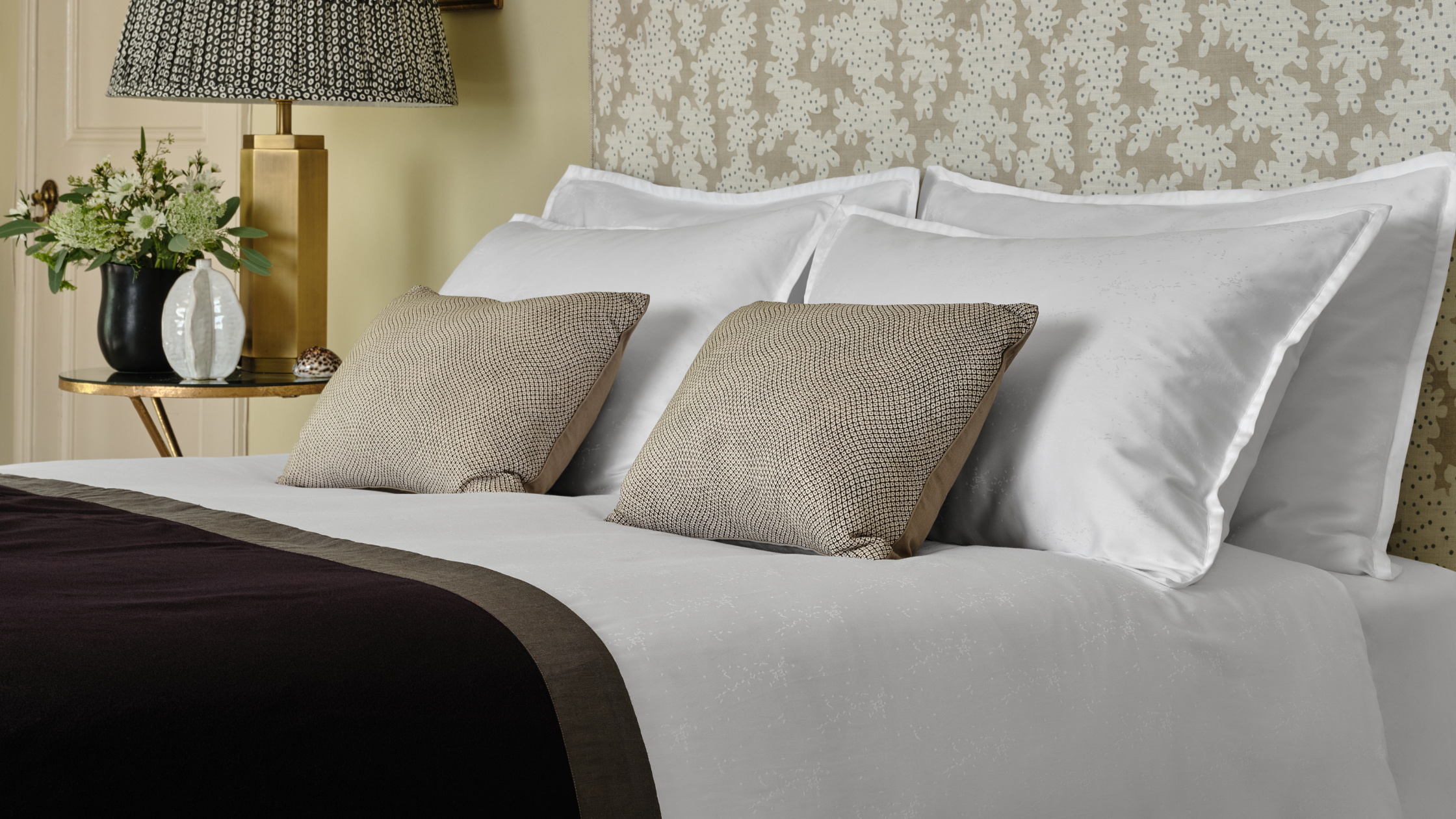 Oriental Collection - Neatly made bed with white pillows and a lamp on a nightstand in the background.